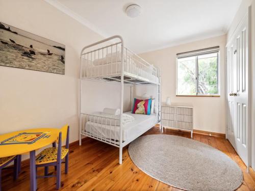 a room with a white bunk bed and a table at Beachfront Bliss, waterfront Geographe bay in Busselton