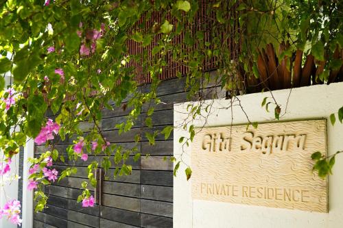a sign in front of a building with pink flowers at Villa Gita Segara Candidasa in Candidasa