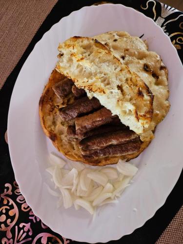a white plate with a sandwich with sausages and onions at Genex-M in Bugojno