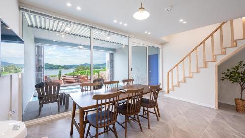 a dining room with a table and chairs and a large window at Namhae Jimong Drawing Pool Villa in Namhae