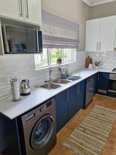 a kitchen with blue cabinets and a washing machine at Spiros Beach Haven in Port Edward