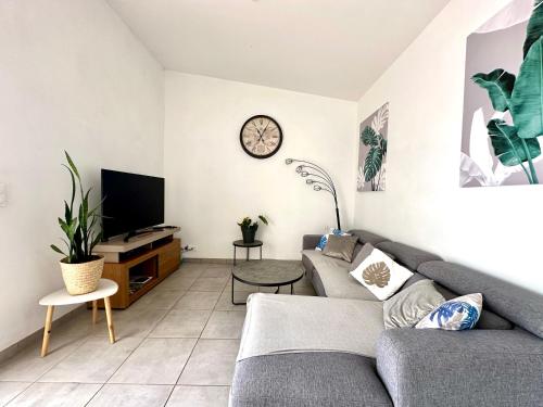 a living room with a couch and a clock on the wall at Mahot in Petite Île