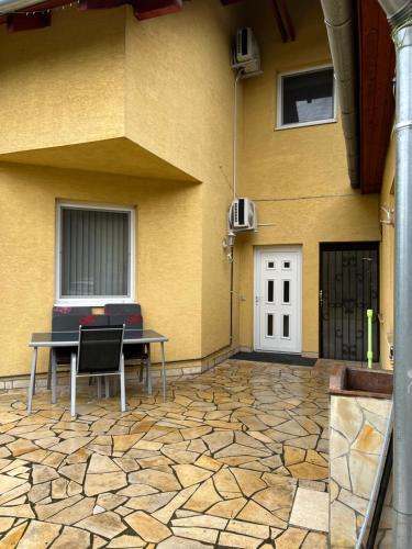 a patio with a table and chairs in front of a building at Monika's Apartman in Érd
