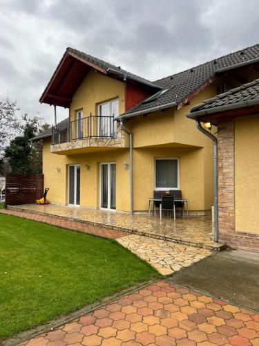 a yellow house with a balcony and a patio at Monika's Apartman in Érd