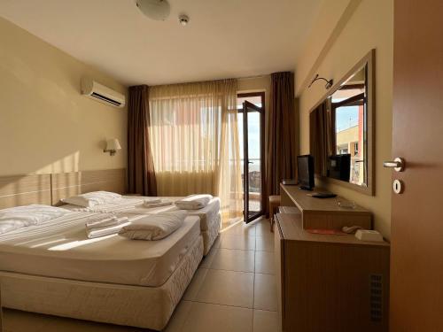 a hotel room with two beds and a television at Александра in Sveti Vlas