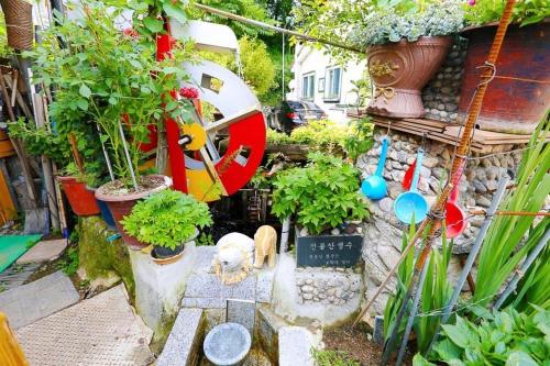 un jardín con macetas y una mesa con una estatua en Osakae Anteo Mulraebang-a Pension, en Yangyang