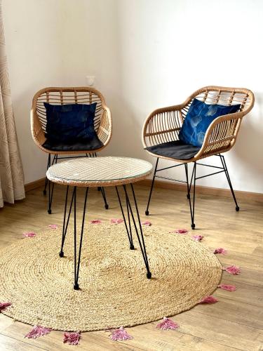 two rattan chairs and a table on a rug at Villa Mahot in Petite Île