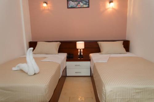 two beds in a room with a white animal on the bed at Elaria Hotel Hurgada in Hurghada