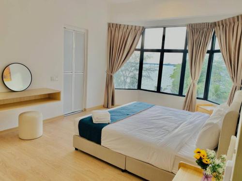 a bedroom with a large bed and large windows at Mutiara Melaka Beach Resort by Glex in Tangga Batu