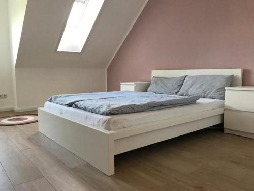 a white bed in a room with a skylight at Nordic Living - 90m² im nordisch modernen Stil in Flensburg