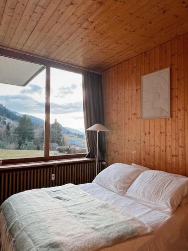 une chambre avec un lit et une grande fenêtre dans l'établissement Blanches Alpes Appartement Megève, à Megève