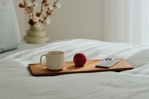 a tray with a coffee cup and an apple on a bed at Apartment C2 - barrierefrei mit großer Südterrasse und Naturblick im "Pine Hill Resort" in Zirchow