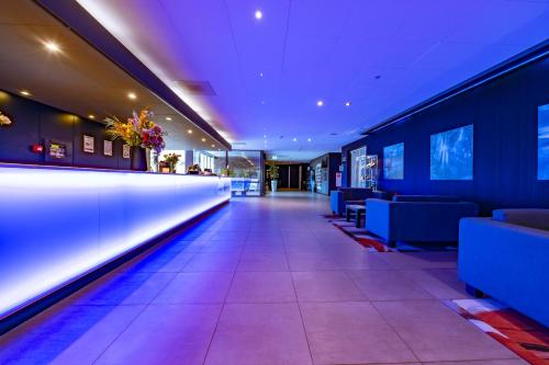 a restaurant with blue walls and a long corridor at Fletcher Hotel-Restaurant Teugel Uden-Veghel in Uden