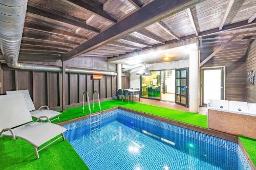 a house with a swimming pool with green grass at Gapyeong Vistahill Pension in Gapyeong