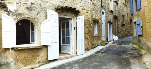 an alley with white doors on a stone building at Les studettes du Beffroi in Cucuron