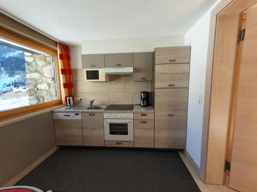 a small kitchen with wooden cabinets and a window at Apart Kathrein in Mathon