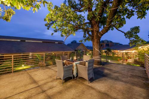 a patio with a table and chairs under a tree at Sterling Orient Woods Pench in Silāri
