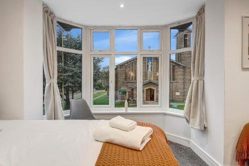 a bedroom with a large window and a bed with towels at Cowley Oxford Stay - Spacious 4 Bed House in Oxford