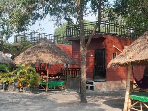 カンポットにあるLa plage de kampot by lee & hap guest houseの木と椅子と木を持つ赤い家