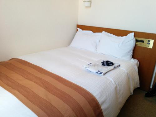 a hotel room with a bed with a towel on it at Hotel Kunimi Gotenba in Gotemba
