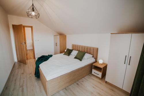 a bedroom with a bed with white sheets and green pillows at Centrum Konferencyjno-Noclegowe in Iwkowa