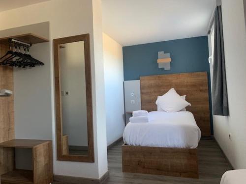 a bedroom with a white bed and a mirror at Val Hôtel Montbéliard Sud in Valentigney