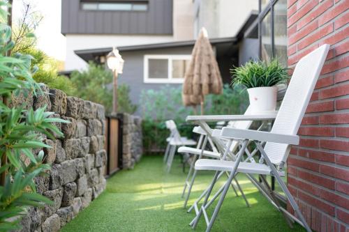 a patio with chairs and a table and a brick wall at Huerim Pool Villa Private Pension in Gyeongju
