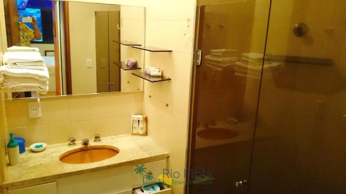 uma casa de banho com um lavatório e um chuveiro com um espelho. em Apart Hotel Leblon Ocean no Rio de Janeiro