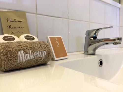 a bathroom sink with a happy monday sign and towels at Ashleigh Court Motel-Christchurch Hagley Park in Christchurch