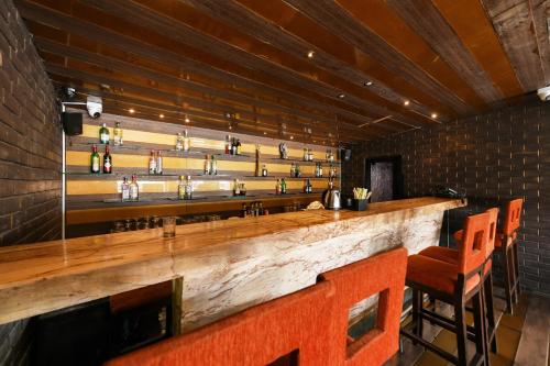 a bar with a wooden counter and some chairs at Hotel Roopa in Mysore