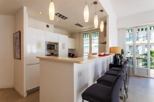 une cuisine avec un bar et des tabourets dans l'établissement METROPOLE AP4113 Nice, by Riviera Holiday Homes, à Nice