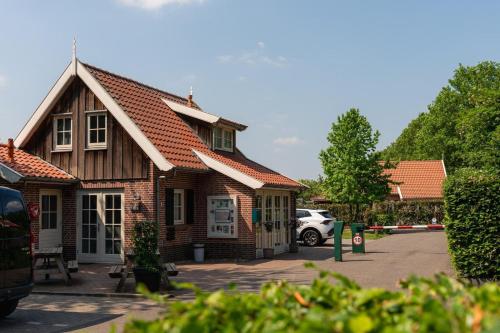 a small brick house with a car parked in a parking lot at Buitengoed het Lageveld 137 in Hoge-Hexel