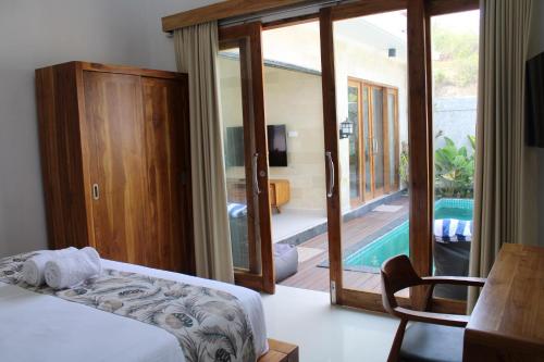 a bedroom with a bed and a balcony with a pool at Layana One in Klungkung