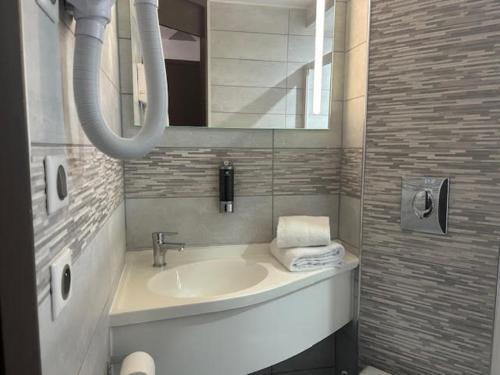 a bathroom with a sink and a mirror at Val Hôtel Montbéliard Sud in Valentigney