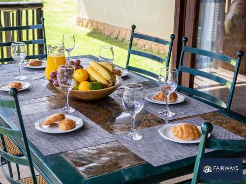 a table with plates of food and glasses of orange juice at Fairways Drakensberg Resort in Drakensberg Garden