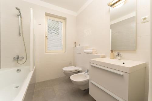 a white bathroom with a toilet and a sink at Casa M Rabac in Rabac
