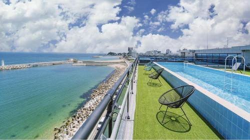 a balcony with a swimming pool on a building next to the ocean at Sokcho The sharp Pension in Sokcho