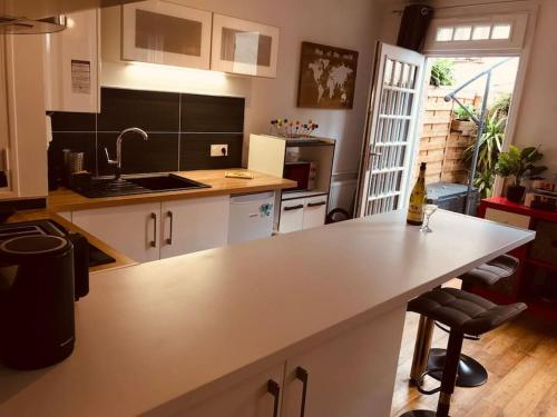 - une cuisine avec un comptoir blanc et un évier dans l'établissement Appart Terrasse Centre ville Parking facile, à Auxerre