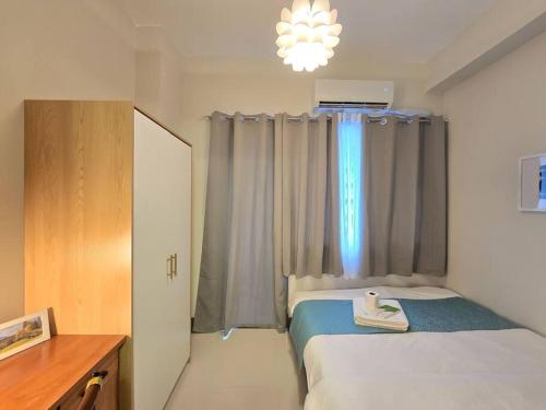 mała sypialnia z łóżkiem i oknem w obiekcie 1BR Condotel with Balcony at FAME Residences #FM62 w mieście Manila