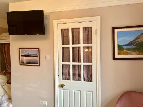 a room with a door with a tv on the wall at Buttermilk Lodge in Clifden