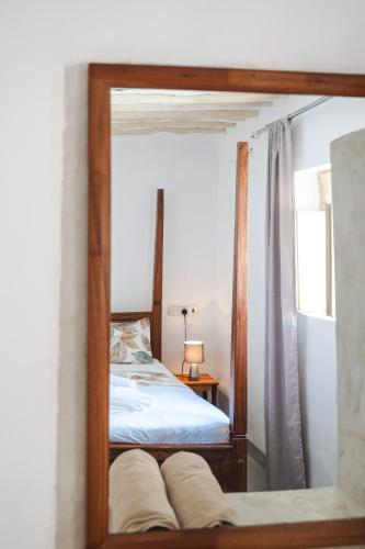a mirror reflection of a bed in a bedroom at Zanzibari holiday home by Liv Zanzibar in Paje