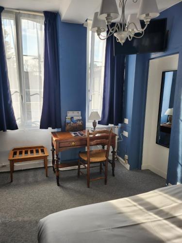 a bedroom with a desk and a bed with blue walls at Hotel Saint Etienne in Caen