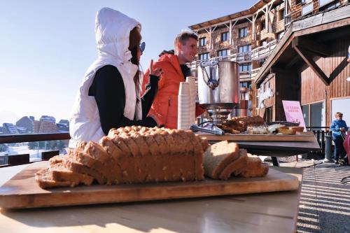 a woman standing next to a table with a loaf of bread at Belambra Clubs Avoriaz - Les Cimes du Soleil in Avoriaz