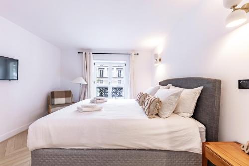 une chambre avec un lit avec une chaise et une fenêtre dans l'établissement Brand New 3 bedrooms Facing Madeleine/St Honoré, à Paris
