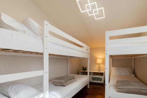 two white bunk beds in a room with a lamp at Casa di Iaio - 90 m2 apt with Free Wi-Fi, Netflix, Home Cinema & Parking in Gorizia