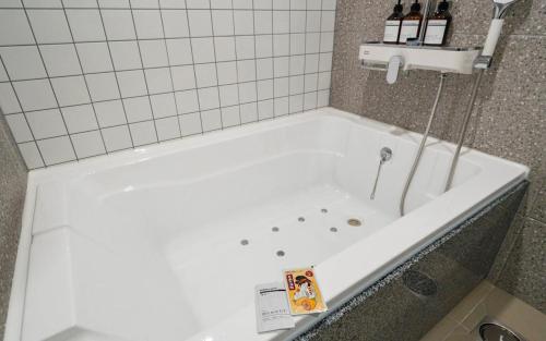 a white bath tub in a bathroom with bottles of wine at Rosy Hotel in Cheongju