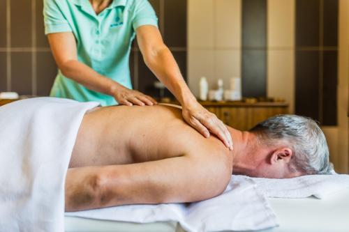 a woman giving a man a back massage at Lázeňský a Wellness hotel NIVAMARE in Luhačovice