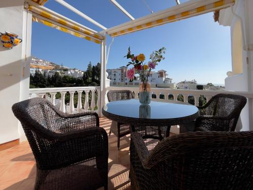 a table with chairs and a vase of flowers on a balcony at Rd02 La Casa Hermosa in Torrox