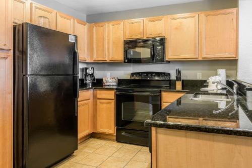 a kitchen with a black refrigerator and wooden cabinets at Bluegreen Vacations Fountains, an Ascend Collection Resort in Orlando