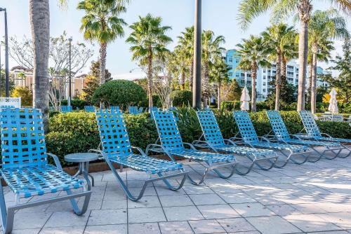 a row of blue chairs on a sidewalk with palm trees at Bluegreen Vacations Fountains, an Ascend Collection Resort in Orlando